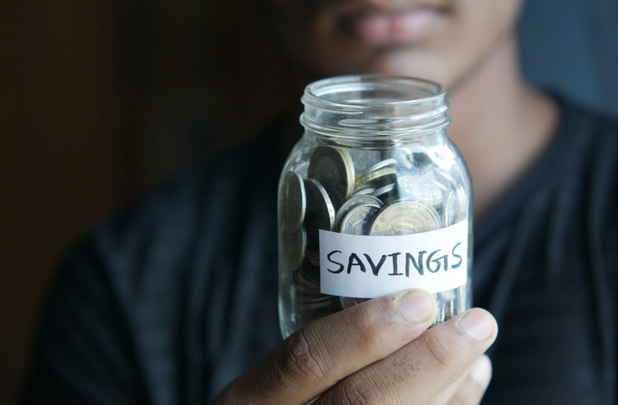 a man holding a jar with a savings label on it