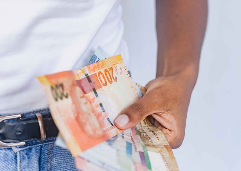 a person holding a bunch of money in their pocket