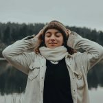 woman in beige coat covering her eyes with her hand