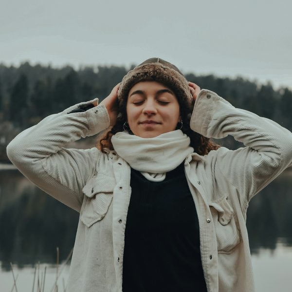 woman in beige coat covering her eyes with her hand