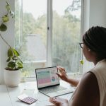 a woman sitting at a table using a laptop computer