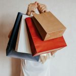 Person holding colorful shopping bags in front of face