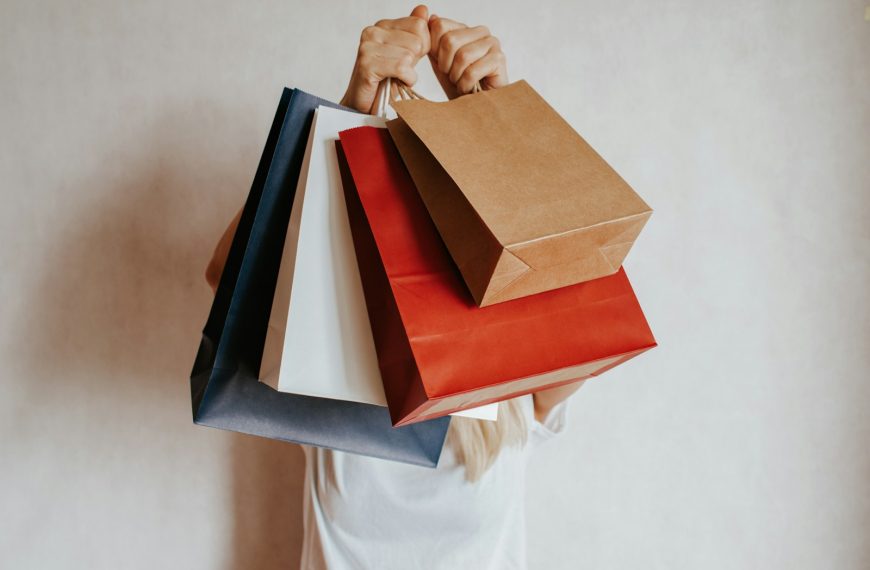Person holding colorful shopping bags in front of face