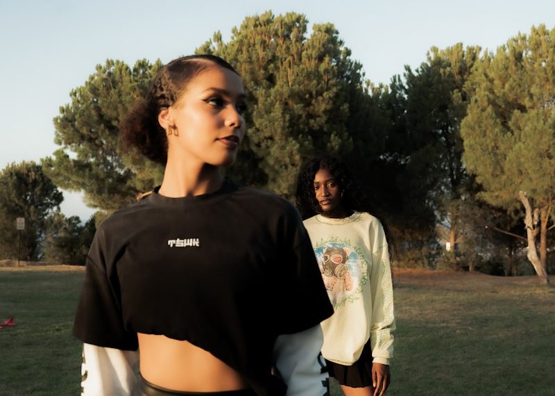 Two women posing in a grassy outdoor setting.