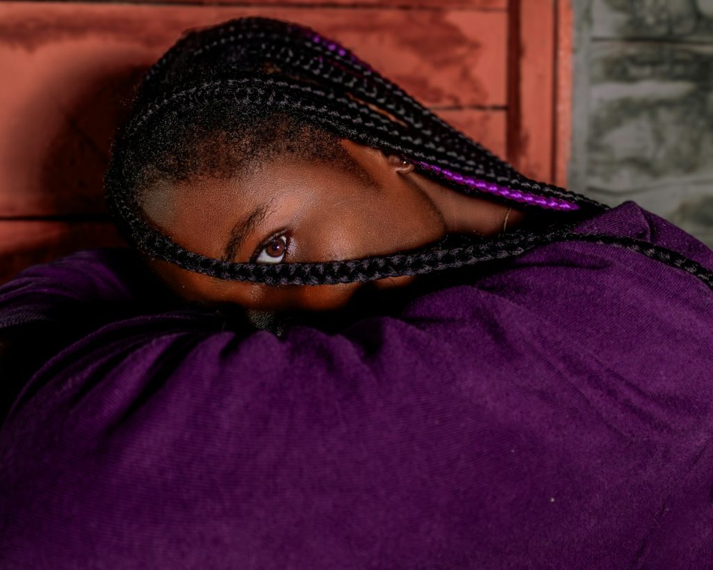 A girl with braids peers through her braids.