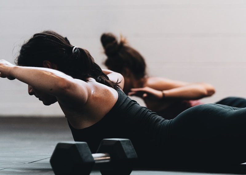 woman in black tank top and black leggings lying on black floor
