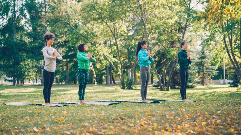 Four women practicing yoga in a park
