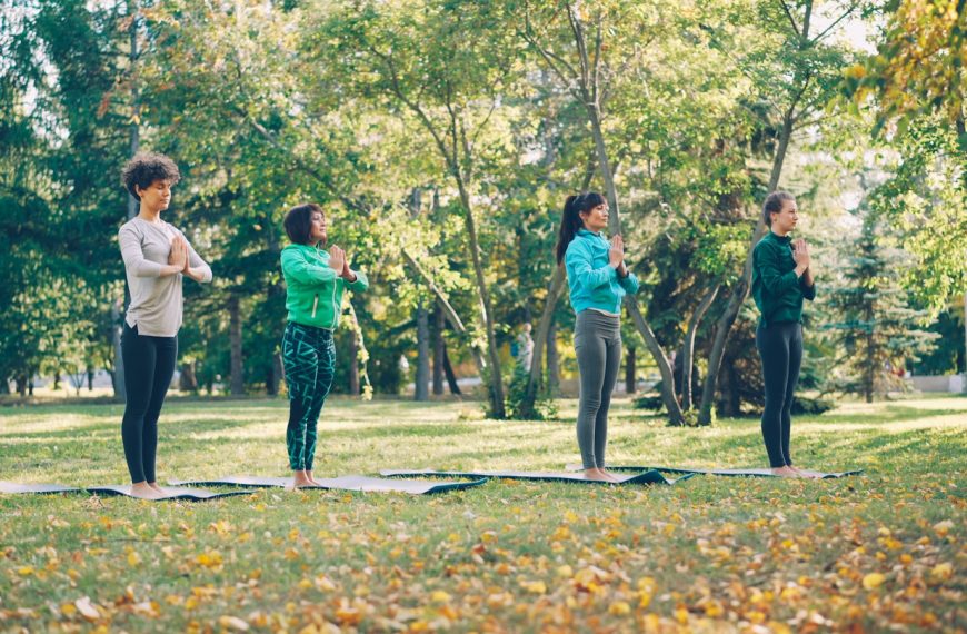 Four women practicing yoga in a park
