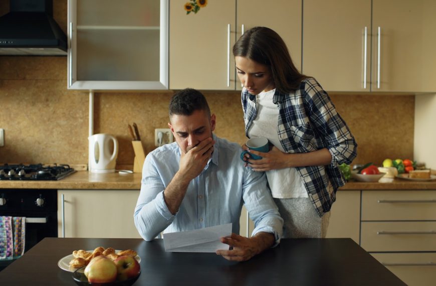 Couple looking stressed over bills at kitchen table.