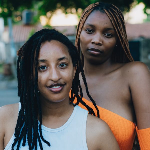 Two women posing outdoors with trees in background