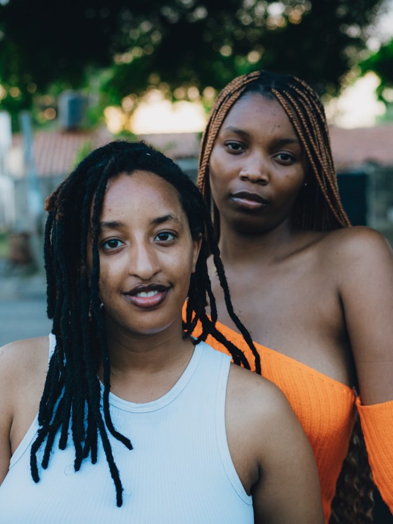 Two women posing outdoors with trees in background