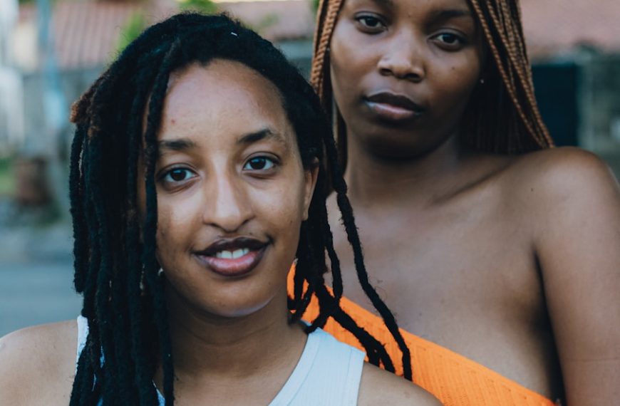 Two women posing outdoors with trees in background