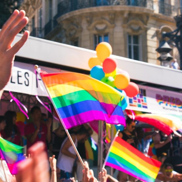 people holding yellow, green, blue, and purple flag