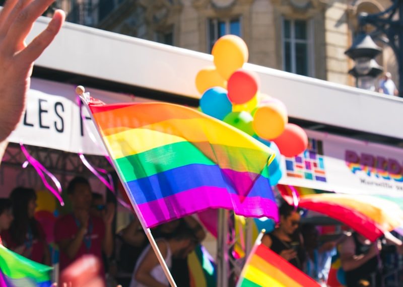 people holding yellow, green, blue, and purple flag