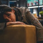 a woman sitting on a couch with her head on her hand