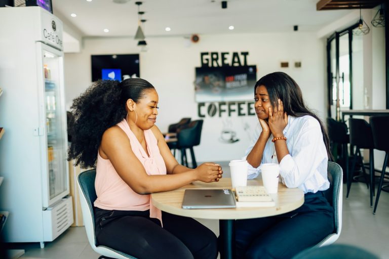 A couple of women sitting at a table with a laptop
