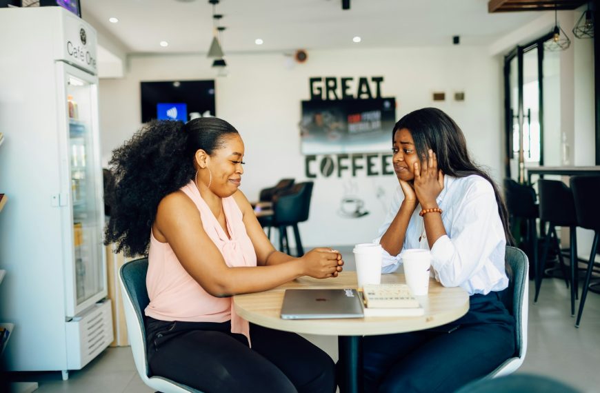 A couple of women sitting at a table with a laptop