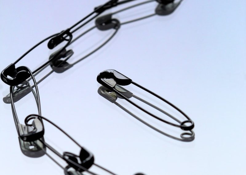 silver safety pin on white paper
